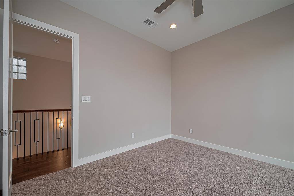 The hallway features engineered wood floors and a contemporary wrought iron railing, adding a modern touch to the upper level. Just down the hall from the gameroom is Bedroom #3, measuring 12.11 x 11.9. While it’s the smallest of the bedrooms, it’s still generously sized and includes a ceiling fan and recessed lighting for comfort and style.