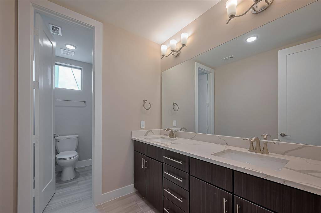Located between Bedroom #3 and Bedroom #4, Bath #3 features a long vanity with two rectangle-shaped undermount sinks, complemented by a quartz countertop. Ample storage is provided with four drawers between the sinks. A long wall mirror and over-mirror lighting brighten the space, while the separate bathing area adds convenience. This setup is ideal for a shared bath, offering both privacy and functionality.