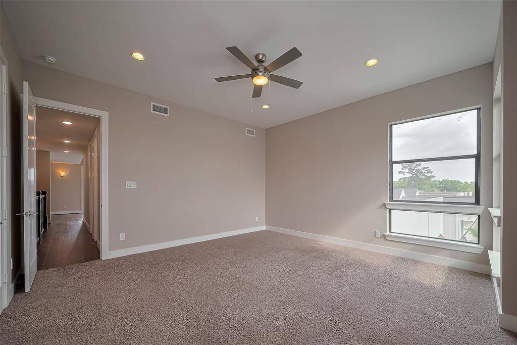 At the opposite end of the 3rd-floor hallway is Bedroom #4, featuring a ceiling fan and recessed lighting for a comfortable, well-lit space. The soft carpet adds warmth to the room and helps muffle noise between floors, creating a quieter and more private environment.