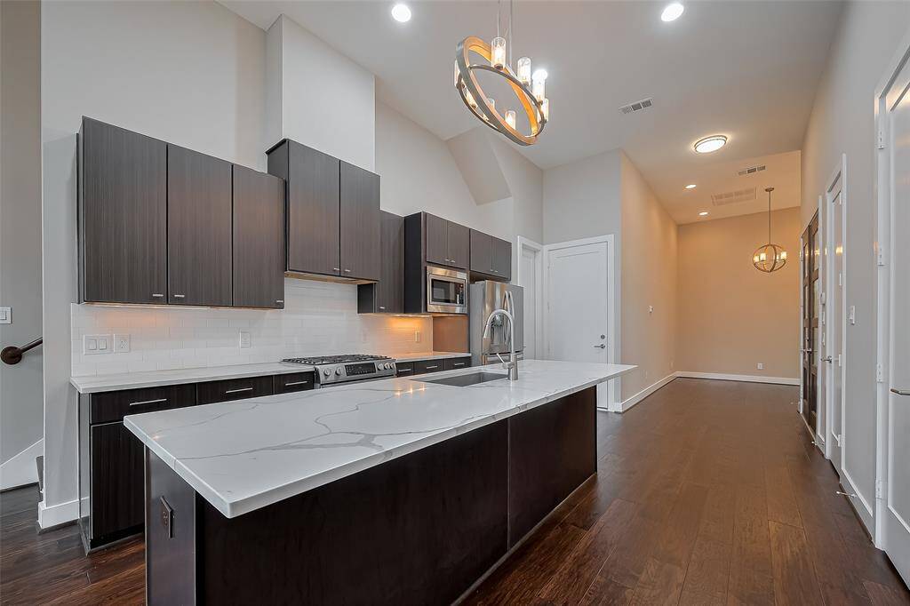 The spacious 17 x 12.6 kitchen is both stylish and functional, featuring sleek cabinetry with under-cabinet lighting, quartz countertops, a classic subway tile backsplash, and stainless steel appliances. The long breakfast bar is perfect for saddle stools—great for casual dining, morning coffee, or serving buffet-style during holidays and game day gatherings with friends. A true centerpiece for everyday living and entertaining.