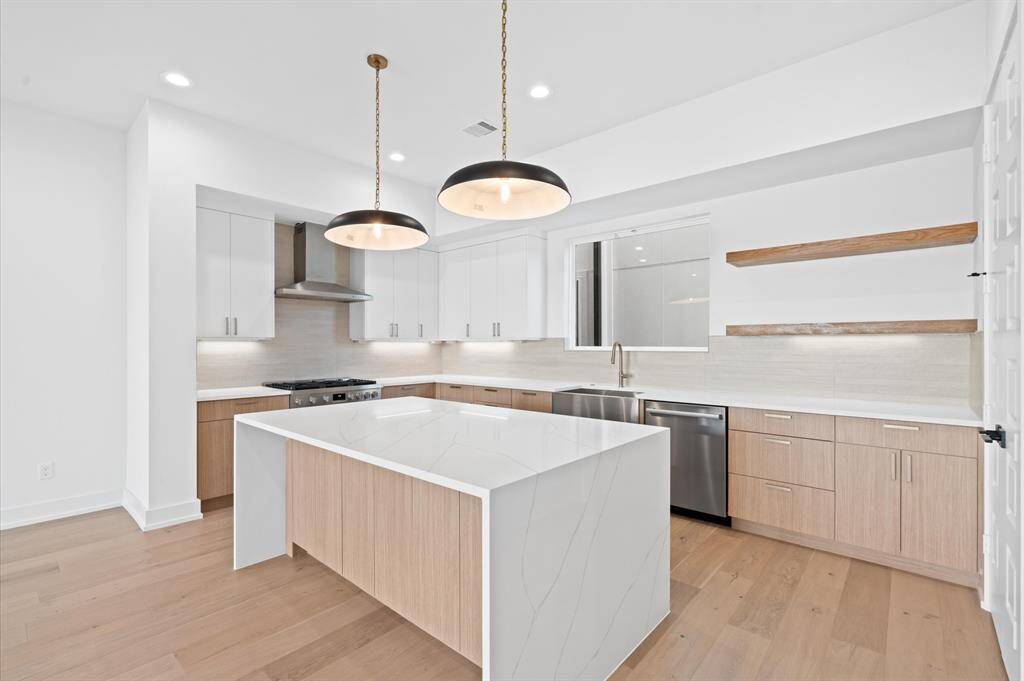 Quartz waterfall island, modern shaker cabinets, and stainless steel Bosch appliances throughout the kitchen