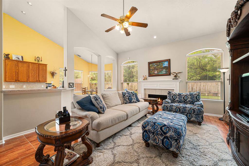 High vaulted ceilings and cozy fireplace flanked by stately windows emphasize the charm and warmth of the family room