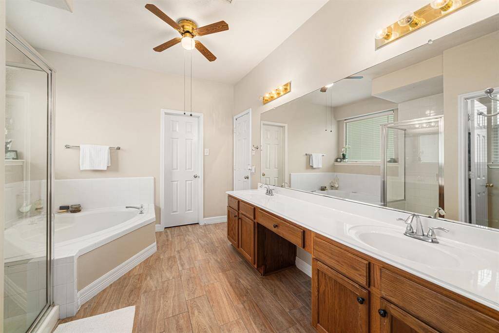 Spacious Primary Bathroom with double vanities, great counter space, ample lighting,  ceiling fan and large garden tub. Two separate master closets