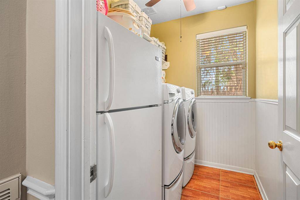 The versatile laundry room features ample space for a full-sized refrigerator and natural lighting to bring a little sunshine to your household tasks