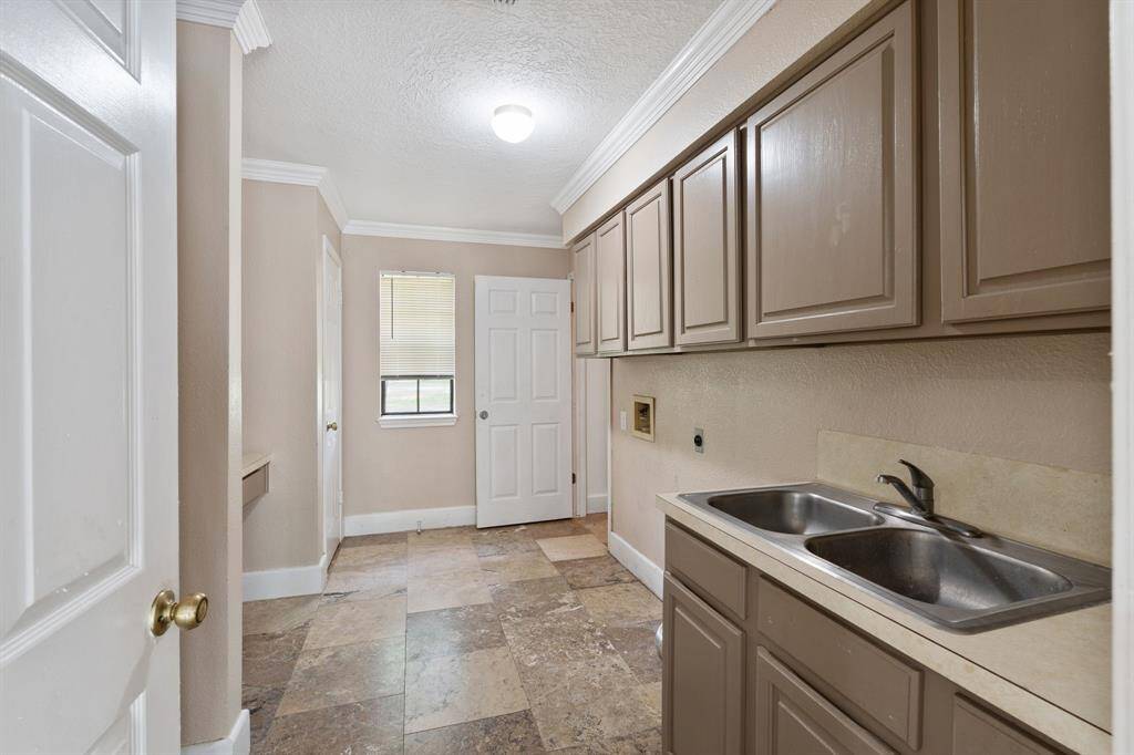 Utility room with ample storage, featuring upper and lower cabinets, and sink.