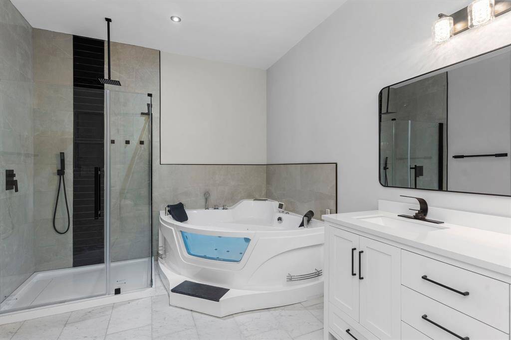 This bathroom features dual vanity sinks, dual jacuzzi tub, and separate walkin shower.