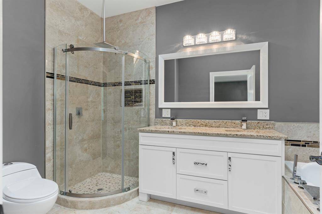 This bathroom features dual vanity sinks, walk in shower, and an oversized jacuzzi tub.