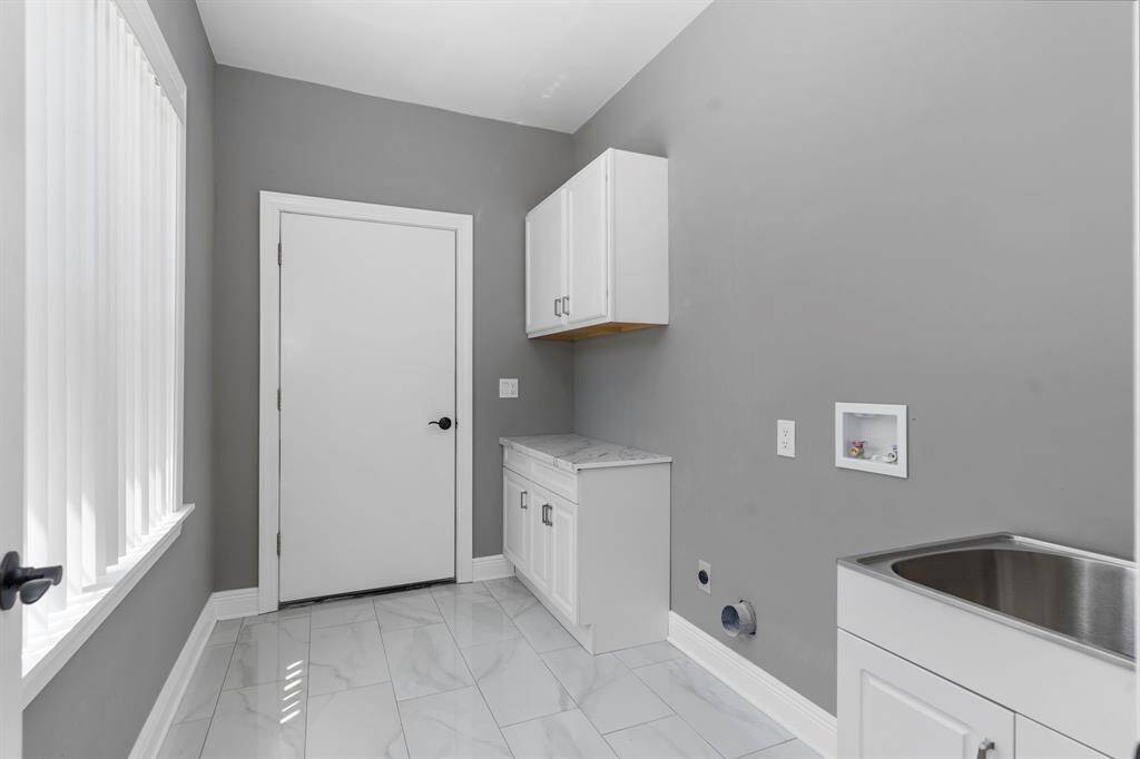 Newly remodeled utility room has washer/dryer connections, cabinets for additional storage and a sink.