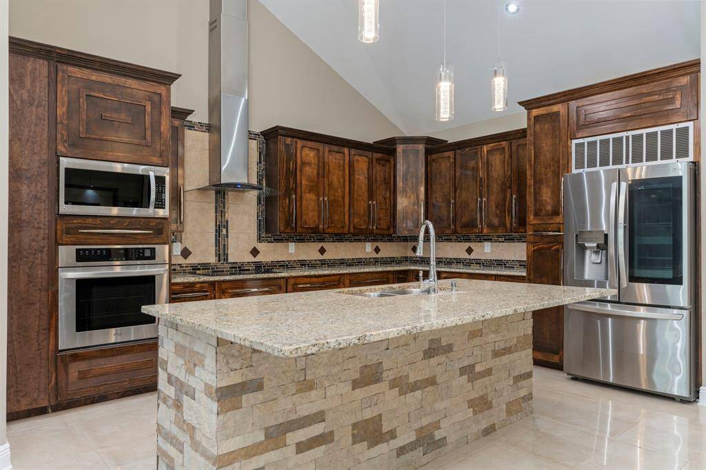 Spacious open concept kitchen featuring a stone island with granite countertops, ample wood cabinetry for maximum storage, and SS appliances.