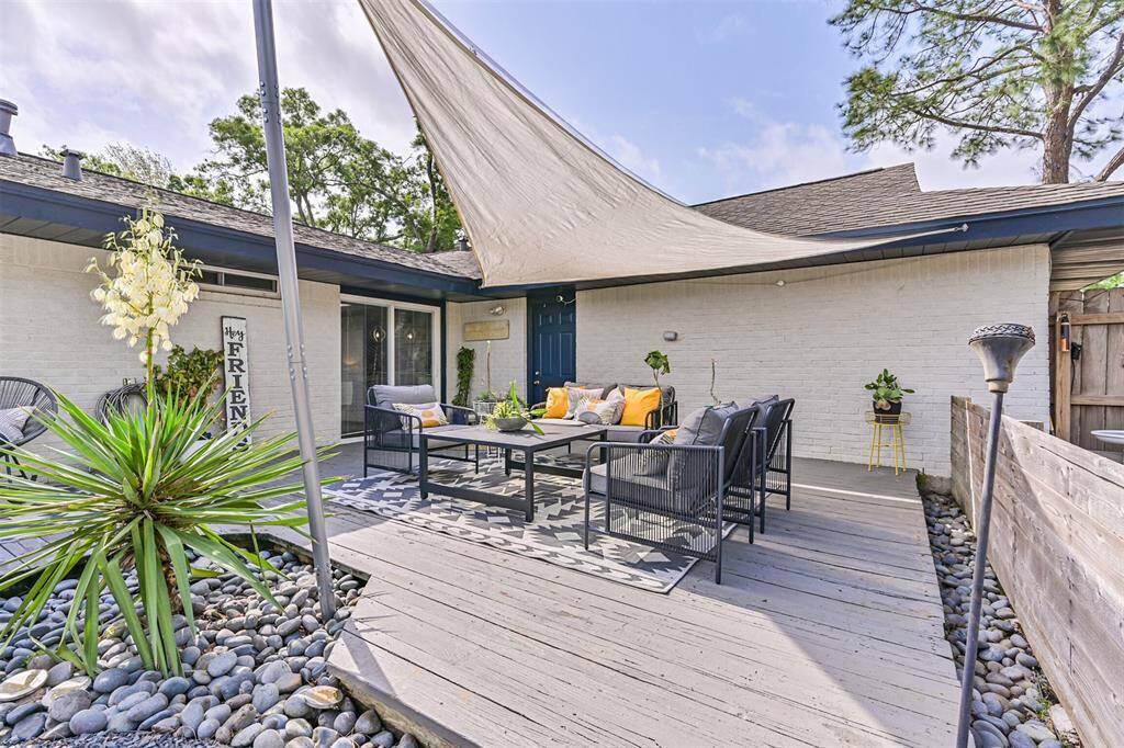 The spacious backyard deck offers plenty of room for outdoor living and entertaining, including convenient access to the garage complete with a modern sun sail shade for comfort and style—perfect for relaxing or hosting under the open sky.