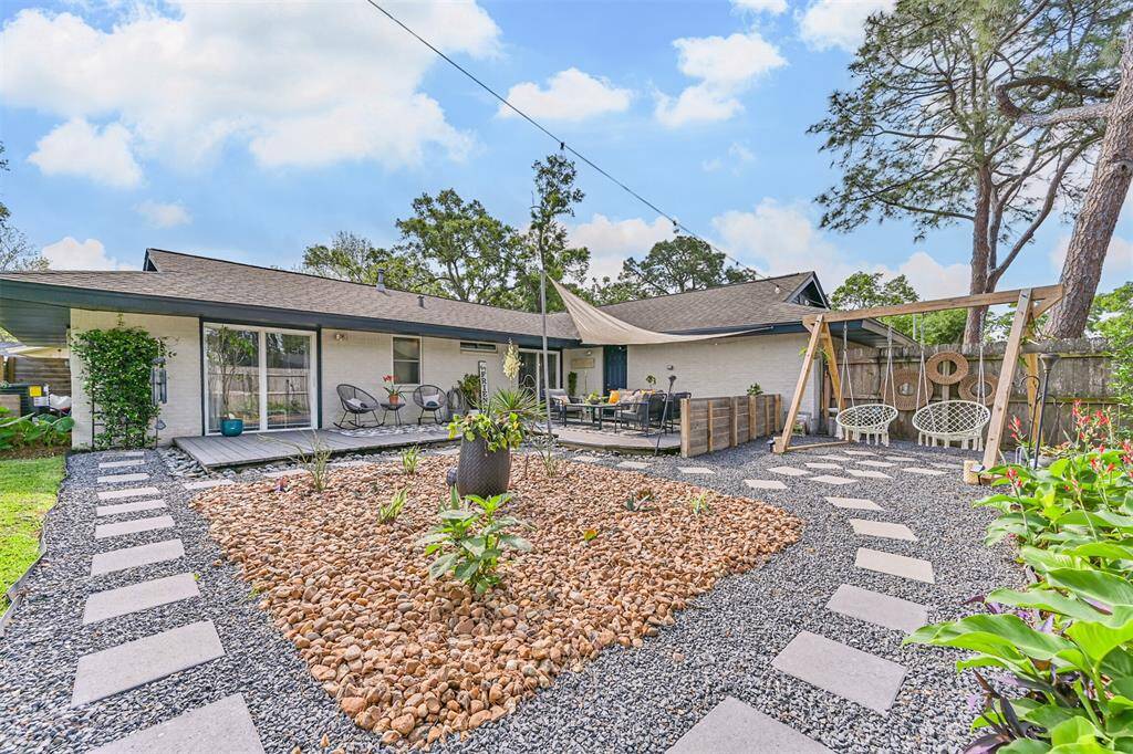 The backyard features a stepping stone walking path set in black gravel, surrounded by river rock landscaping—creating a serene, low-maintenance outdoor space with thoughtful design and natural beauty.