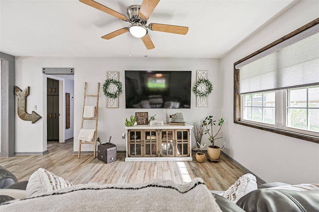 Living room showcases updated windows framed in custom-stained wood with tailored coverings—flooding the space with natural light while adding a touch of craftsmanship.