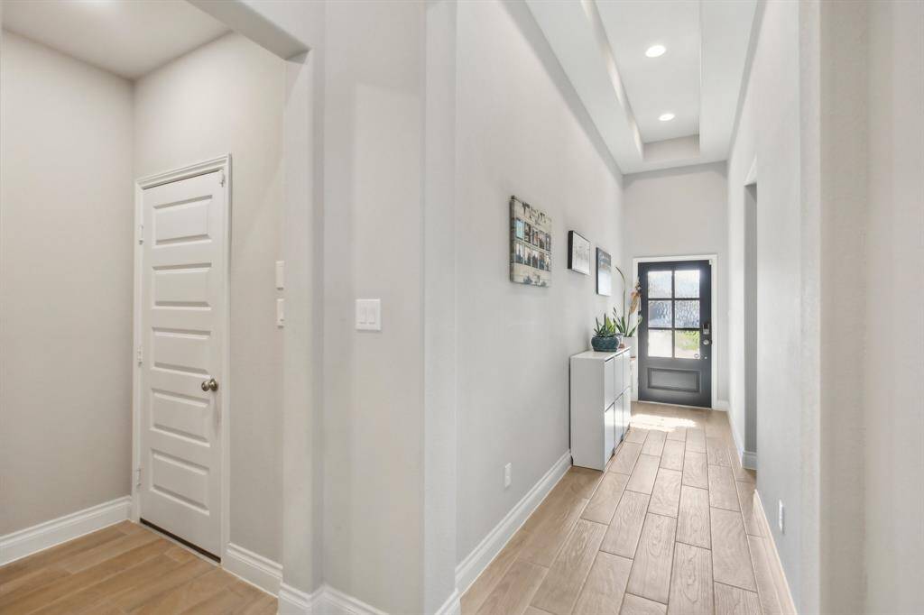 Bright entry features a charming tray ceiling and elegant wood-like ceramic tile, setting the tone for the rest of the home. To the left, you'll find the spacious guest suite, offering privacy and comfort right off the entry.