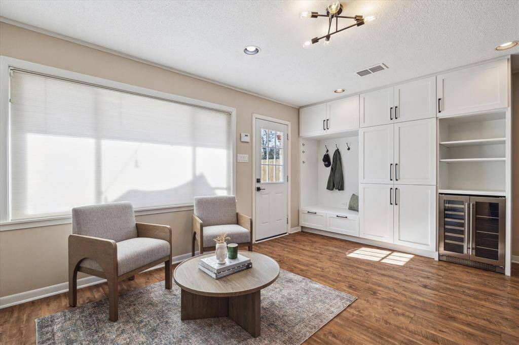 The kitchen is open to a secondary living space with door to the back patio. This room is quite versatile, and can be set up as a relaxing bar/entertaining area (shown here), an additional den, or even a formal dining room. Note the new built in unit with so much storage, and a wine fridge which is included in the sale of the property.
