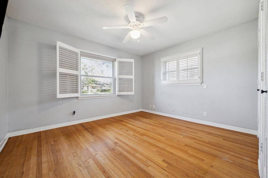 View of the first secondary bedroom, note the wood shutters and original hardwood floors.