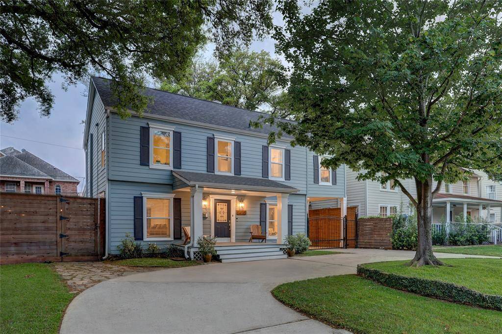 Front elevation framed by mature trees, with a circular driveway offering ample parking for at least three vehicles.