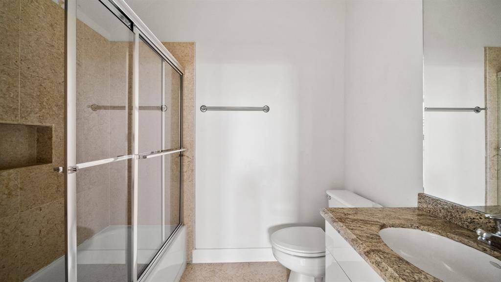 he en-suite bathroom for the secondary first-floor bedroom boasts a tiled shower with a tub and sleek glass sliding door.