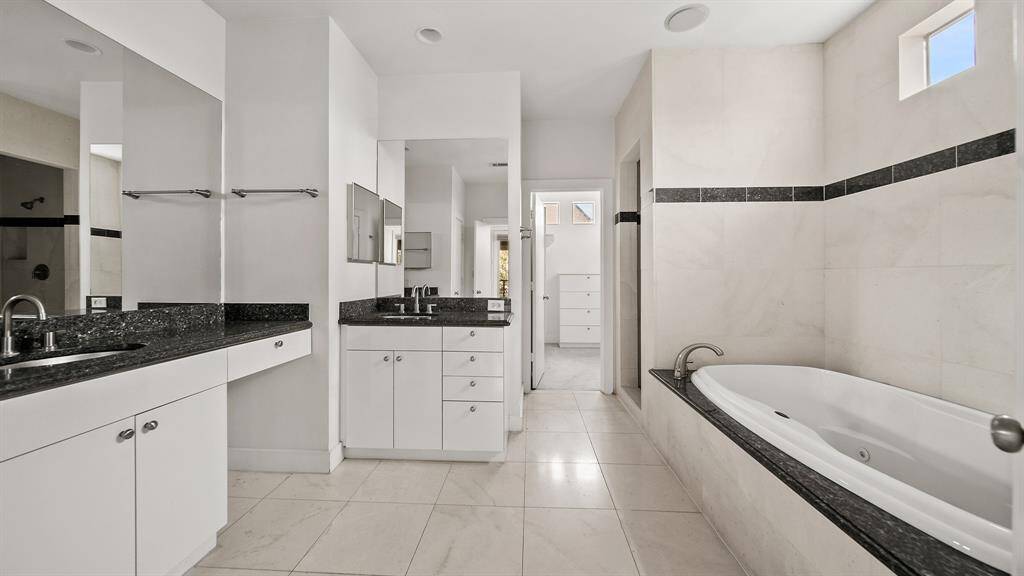 Primary bathroom featuring double sinks with elegant granite countertops, offering both style and functionality.