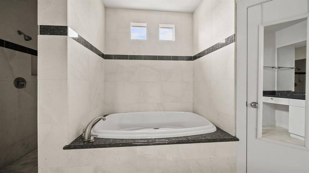 Primary bathroom with a luxurious jetted tub and a separate shower, perfect for relaxation and comfort.