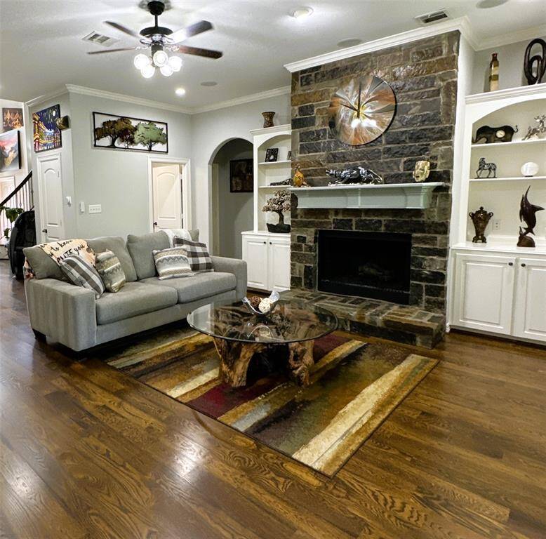 This cozy living room features a stone fireplace, built-in shelves, and hardwood floors.