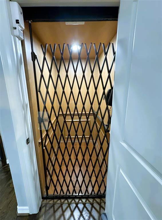This photo shows a home elevator with a wooden interior and a metal accordion gate, providing convenient access between floors.