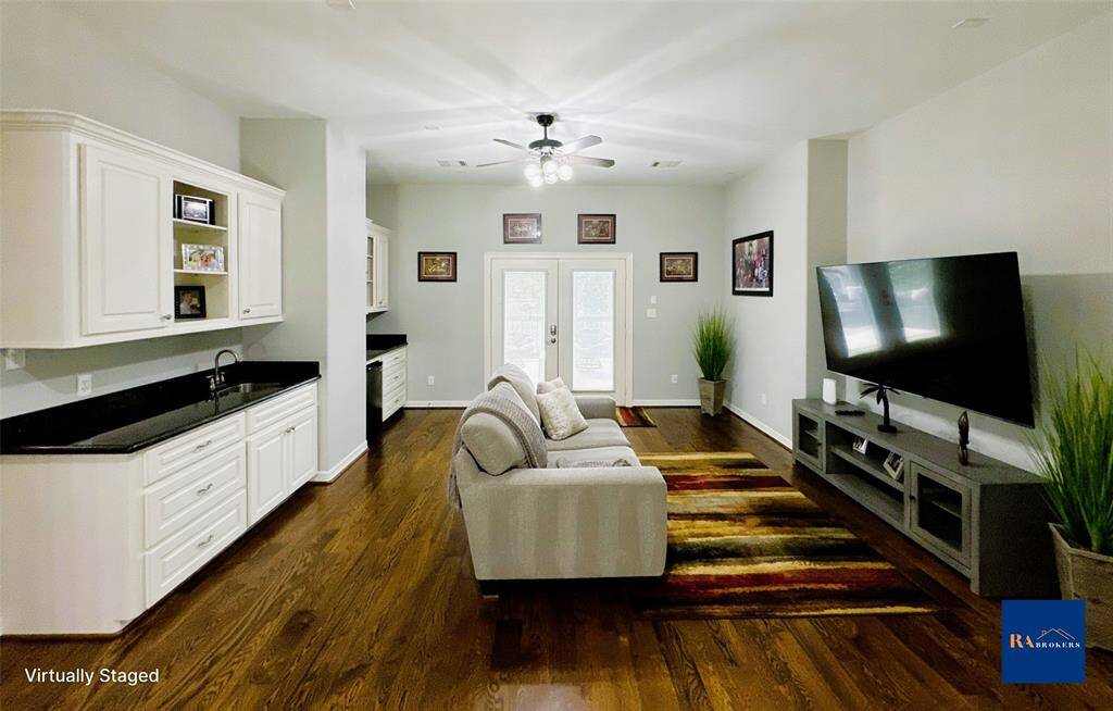 Elevate your entertainment experience in this stylish media room featuring a wet bar, beverage fridge, and French doors opening to the upper porch.
