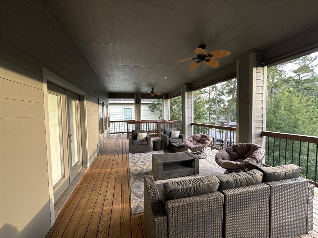 This photo showcases a spacious covered deck featuring comfortable outdoor seating, ceiling fans, and a view of surrounding greenery. Ideal for relaxation and entertaining.