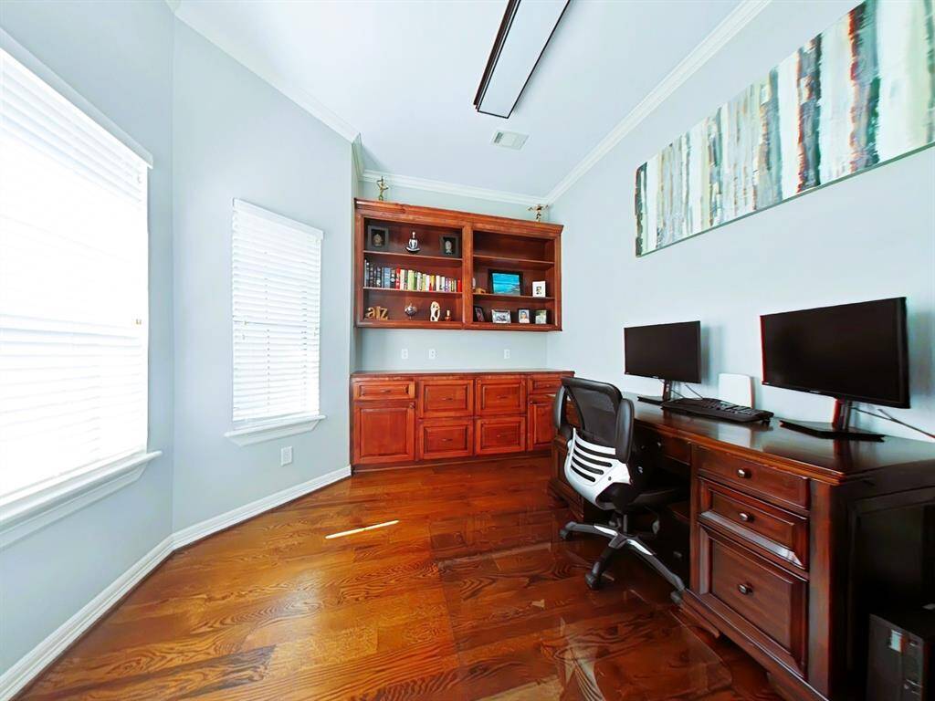 Discover the inviting home office just off the entrance, featuring elegant built-in cabinets and bookshelves.