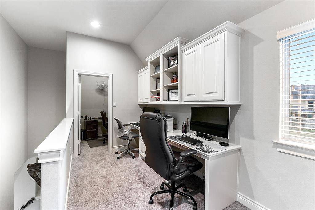 Here’s a closer view of the built-in workspace, featuring dual desks perfect for two people to work simultaneously. The workspace is equipped with ample storage, including built-in cabinets and shelving, keeping everything organized and easily accessible. Large windows bring in plenty of natural light, creating an inviting and productive environment.