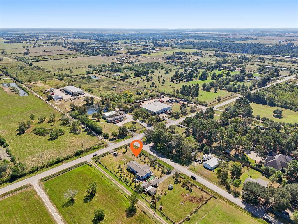 Take in this stunning aerial view of a property nestled in a spacious rural setting, surrounded by expansive land that perfectly balances privacy with open space."