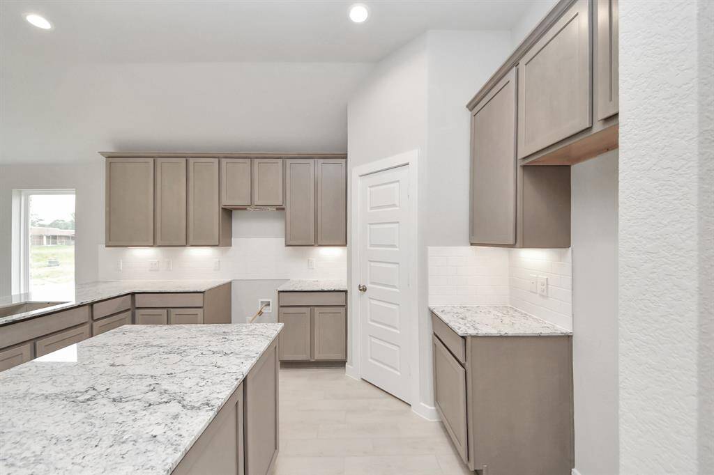 The kitchen is a culinary haven, featuring granite countertops, a tile backsplash, stainless steel appliances, 42” upper cabinets, and undercabinet lighting.