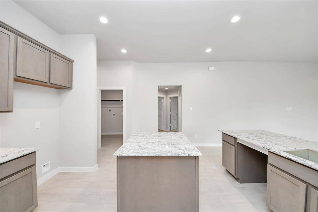 This kitchen is truly a chef's dream! This haven Boasts high ceilings, recessed lighting, stained wood cabinets, granite countertops, stainless steel appliances, a modern tile backsplash.  All of this overlooks your expansive family room, creating a perfect space for culinary delights and family gatherings.