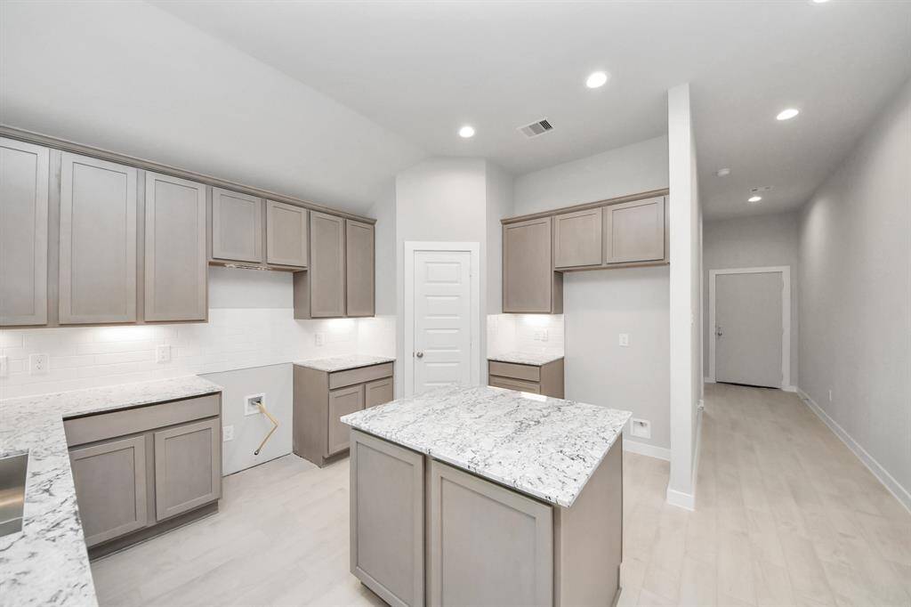This kitchen is truly a chef's dream! This haven Boasts high ceilings, recessed lighting, stained wood cabinets, granite countertops, stainless steel appliances, a modern tile backsplash.  All of this overlooks your expansive family room, creating a perfect space for culinary delights and family gatherings.