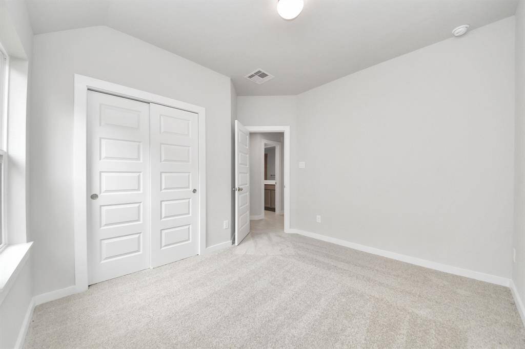 Secondary bedroom features plush carpeting, large windows that let in plenty of natural light, bright paint, and spacious closets.
