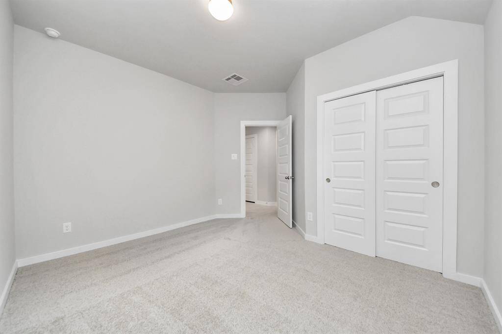 Secondary bedroom features plush carpeting, large windows that let in plenty of natural light, bright paint, and spacious closets.