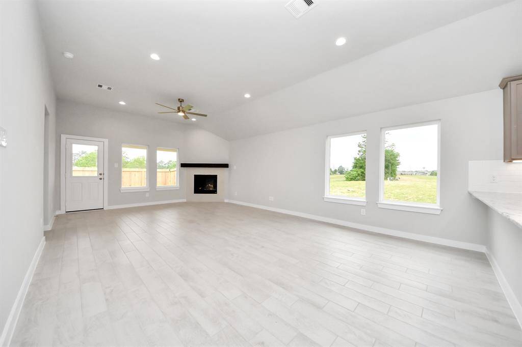 Welcome family and guests to your charming living room! With its high ceilings, recessed lighting, ceiling fan, custom paint, beautiful flooring, and large windows that let in abundant natural light, this room is perfect for gatherings.