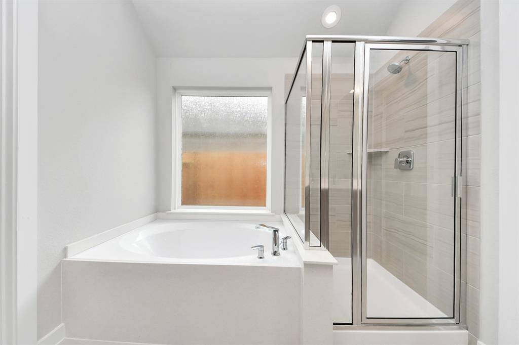This additional view of the primary bath features a walk-in shower with the tile surround and separate garden tub perfect for soaking after a long day.