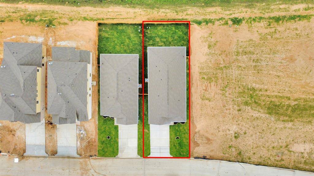 An aerial view of a spacious subdivision lot, highlighting a well-maintained yard and a fully fenced perimeter, offering both privacy and expansive outdoor space.