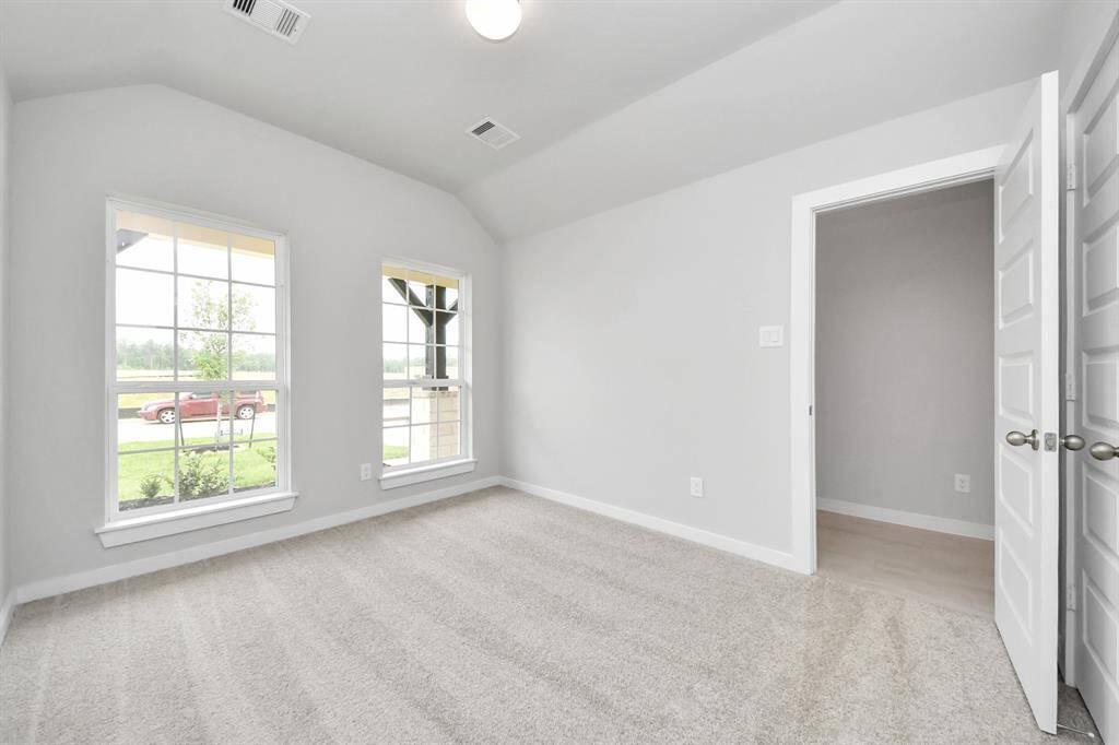Secondary bedroom features plush carpeting, large windows that let in plenty of natural light, bright paint, and spacious closets.