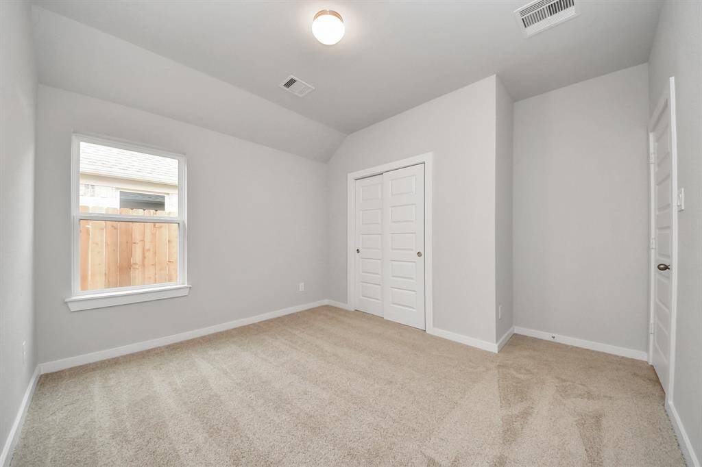 Secondary bedroom features plush carpeting, large windows that let in plenty of natural light, bright paint, and spacious closets.