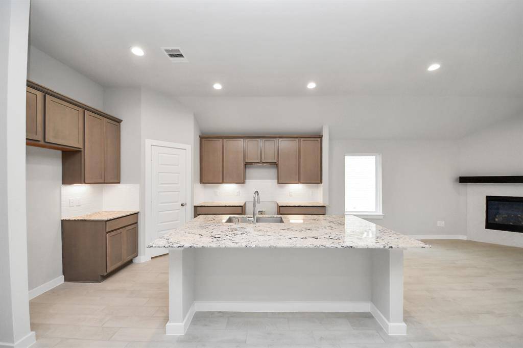 The kitchen is a culinary haven, featuring granite countertops, a tile backsplash, stainless steel appliances, 42” upper cabinets, and undercabinet lighting.