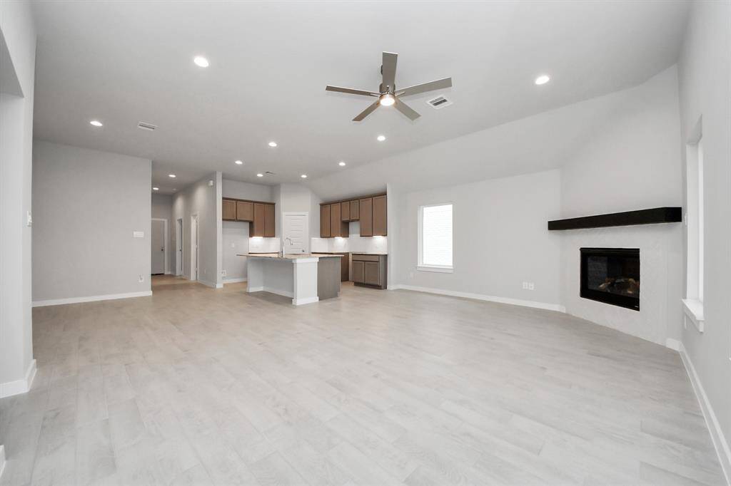 Welcome family and guests to your charming living room! With its high ceilings, recessed lighting, ceiling fan, custom paint, beautiful flooring, and large windows that let in abundant natural light, this room is perfect for gatherings.