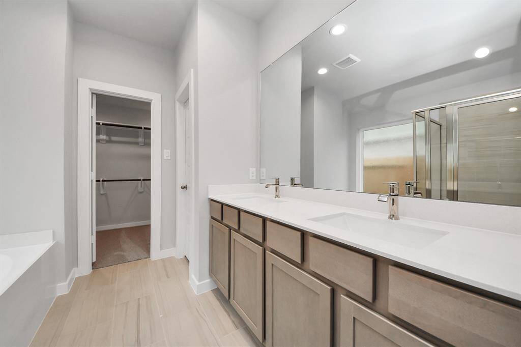 Elevate your daily routine at the elegant vanity, now equipped with double sinks, light countertops, modern hardware, and beautiful recessed lights.