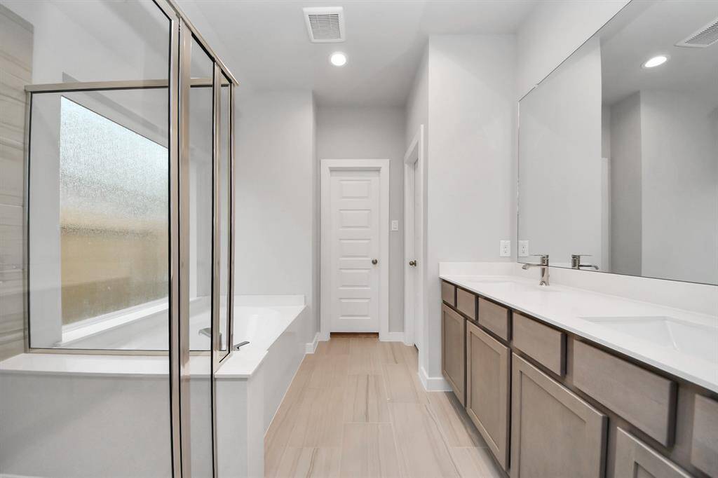 This additional view of the primary bath features a walk-in shower with the tile surround and separate garden tub perfect for soaking after a long day.