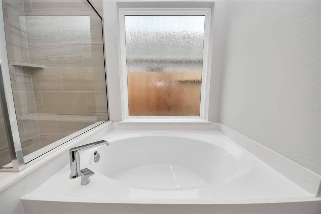 Indulge in a spa-like retreat within the confines of this primary bathroom. Delight in a spacious walk-in shower enveloped in stylish tile surround, unwind in a separate garden tub adorned with custom detailing.