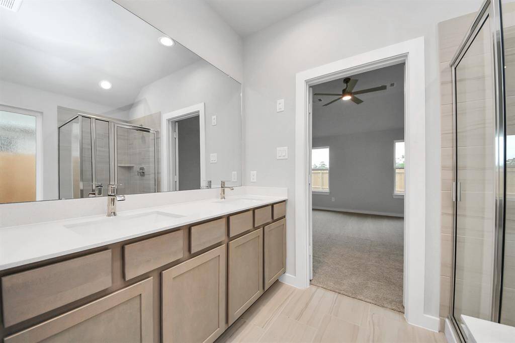 Elevate your daily routine at the elegant vanity, now equipped with double sinks, light countertops, modern hardware, and beautiful recessed lights.
