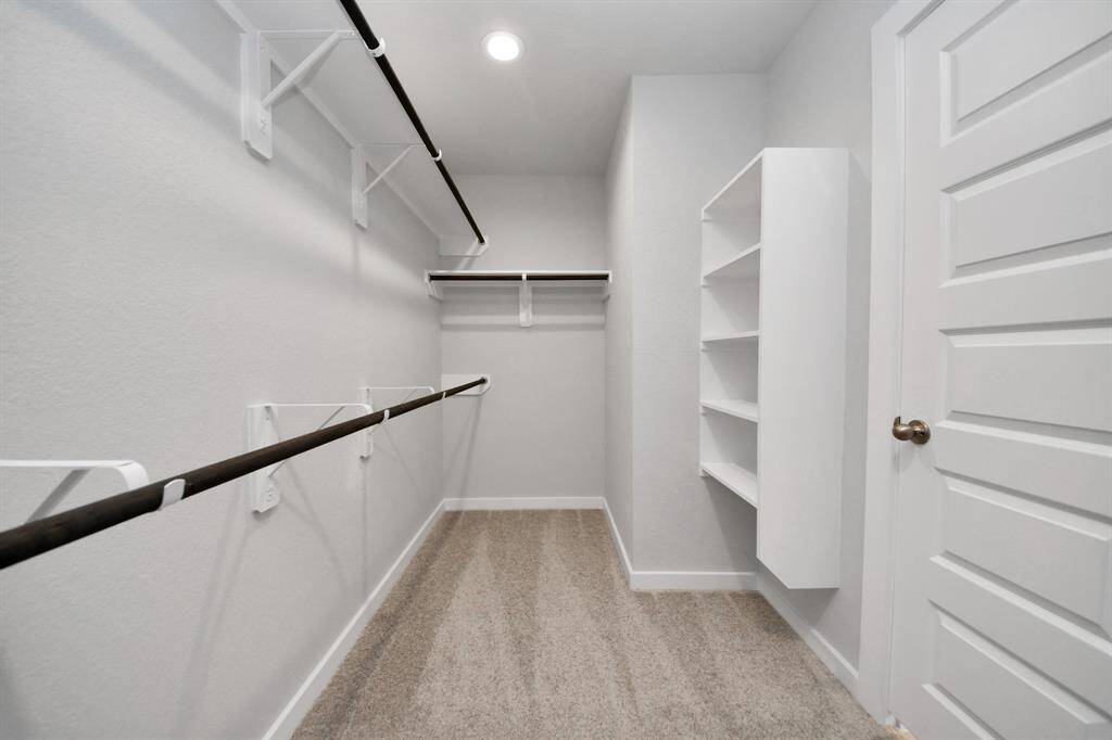 Walk-in closet that epitomizes luxury and practicality. This generously sized space features built-in shelving, offering abundant room for impeccable organization. High ceilings and recessed lighting create a bright and welcoming ambiance.
