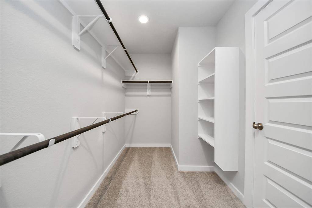 Step into a walk-in closet that defines luxury and functionality. This generously sized space boasts built-in shelving, providing ample room for organization.