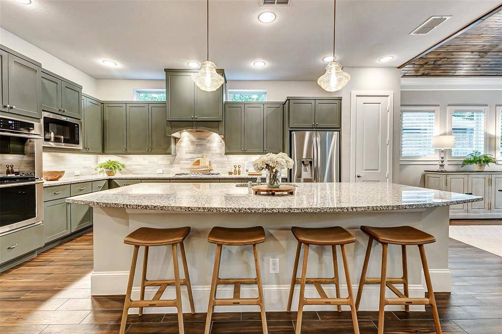 The massive breakfast bar provides additional seating, making it the perfect spot for casual meals or a quick bite. Beautiful granite countertops pair effortlessly with two stylish pendant lights, adding both elegance and functionality to this inviting space.