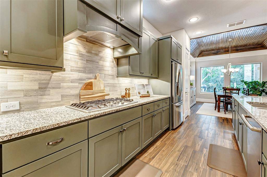Additional features include a gas cooktop paired with a vent hood that seamlessly integrates with the cabinetry, offering a sleek, modern design with a minimalist profile. The kitchen is further enhanced by double ovens and a built-in microwave, all of which match in style for a cohesive and sophisticated look.